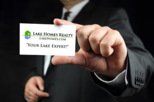 man in suit holding out a Lake Homes Realty Lake Expert business card