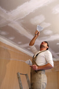 man repairing drywall on ceiling