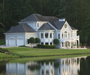 large multi-story white house with two car garage on the waterfront