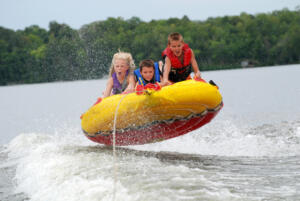 three kids catching air on a tube being pulled behind a boat