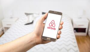 cell phone featuring Airbnb logo being held over bed