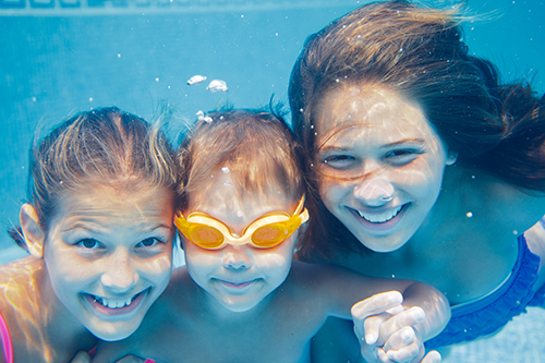 three children smiling under water