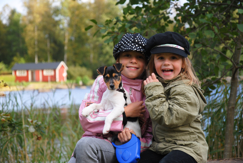 two little girls sitting by lake holding a puppy