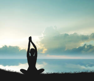 silhouette of woman doing yoga by the lake