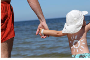 Child in swim trunks holding father's hand at the lake