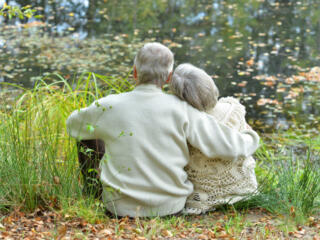 elderly couple hugging next to lake-sm