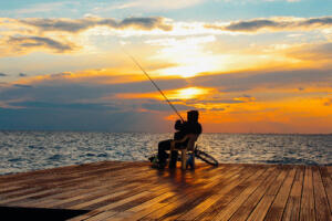 man fishing on the dock at sunset