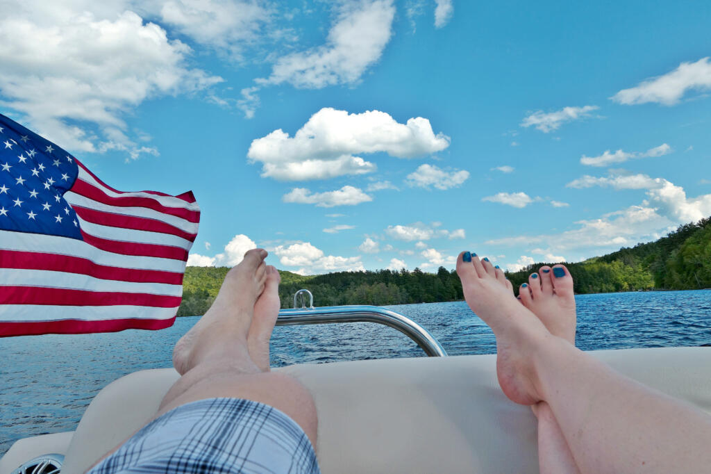 boy and girl feet hanging of the end of boat with American flag