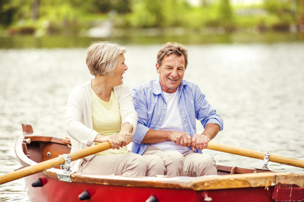 older couple enjoying lake living while rowing a boat
