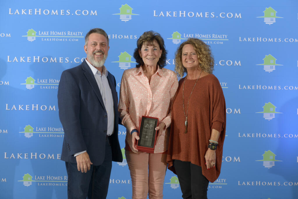 Emily Carter Morris, the winner of Lake Home Realty's Agent of the Year 2019 award, standing next to CEO Glenn Phillips and COO Doris Phillips.