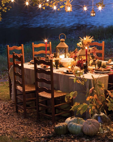 Autumnal al-fresco dining by the lake illuminated by string lights and candles