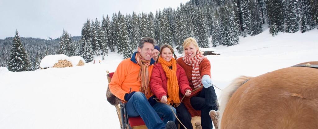 Happy family on horse drawn sleigh ride during the winter