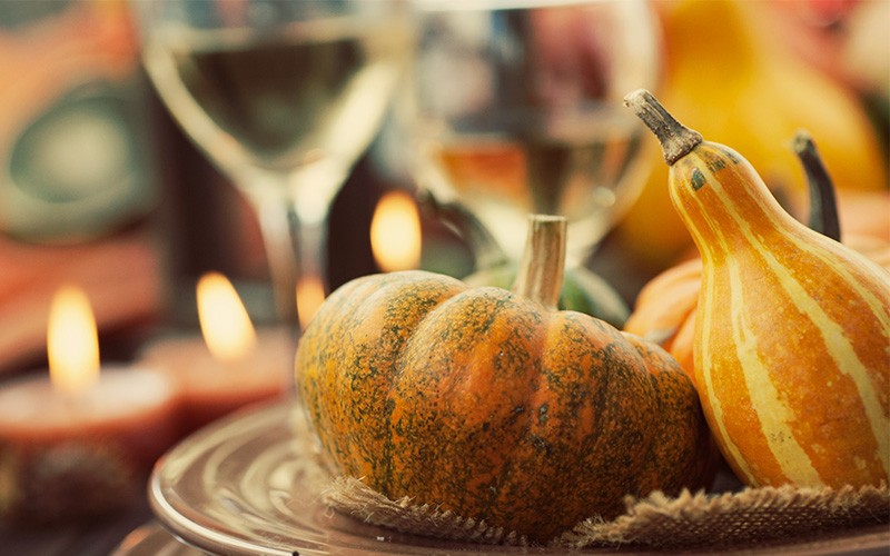 Pumpkins on table setting in front of wine glasses