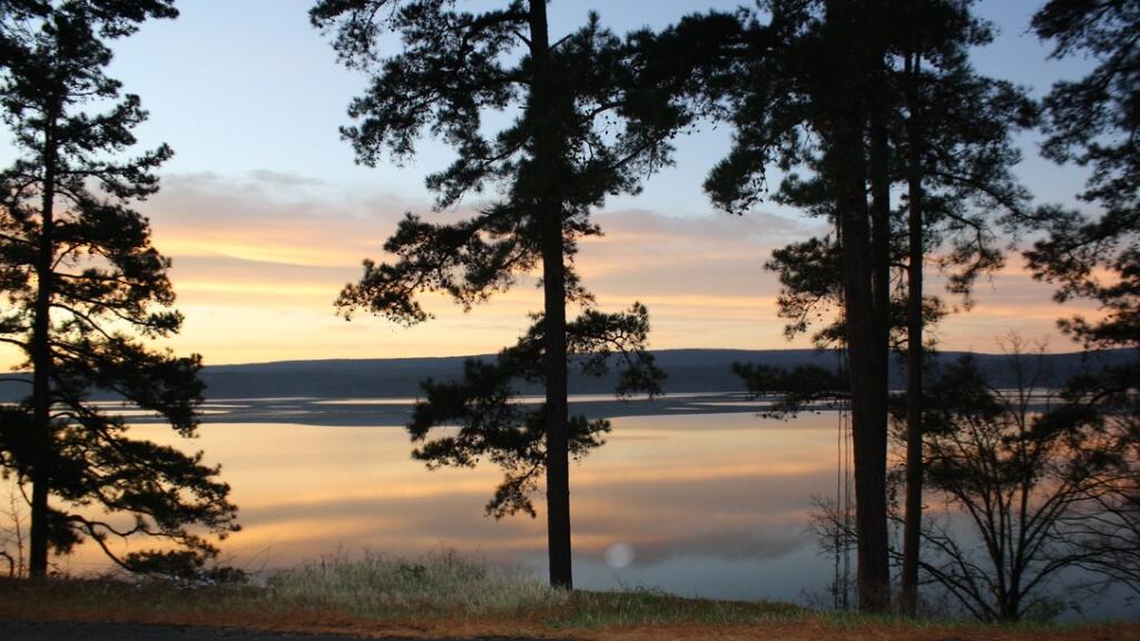 Lake with trees lining shoreline during sunset