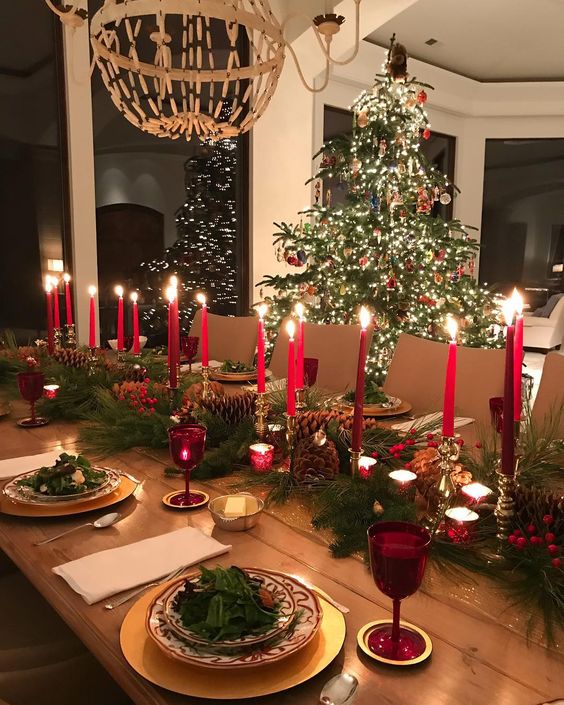 Christmas table setting during night with candles next to Christmas tree