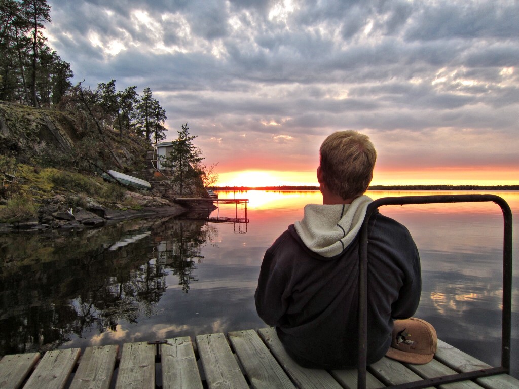 Man sitting on lake dock enjoying sunset