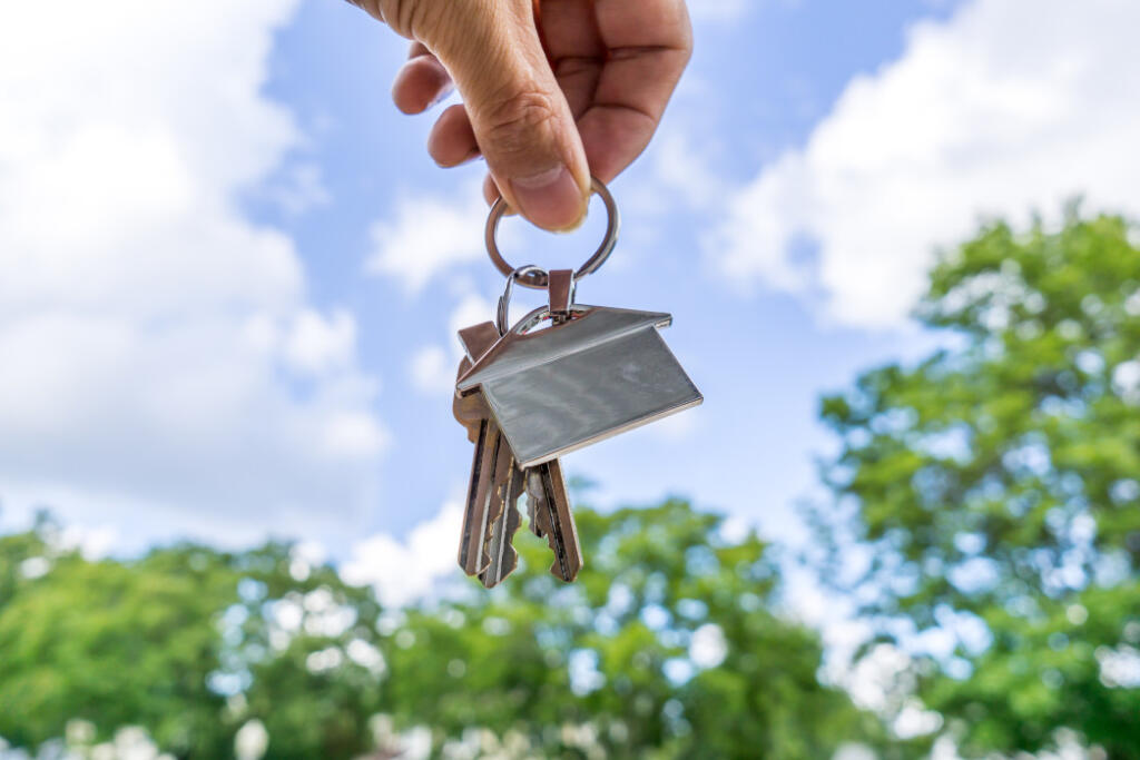Person holding set of keys with house keychain in the air