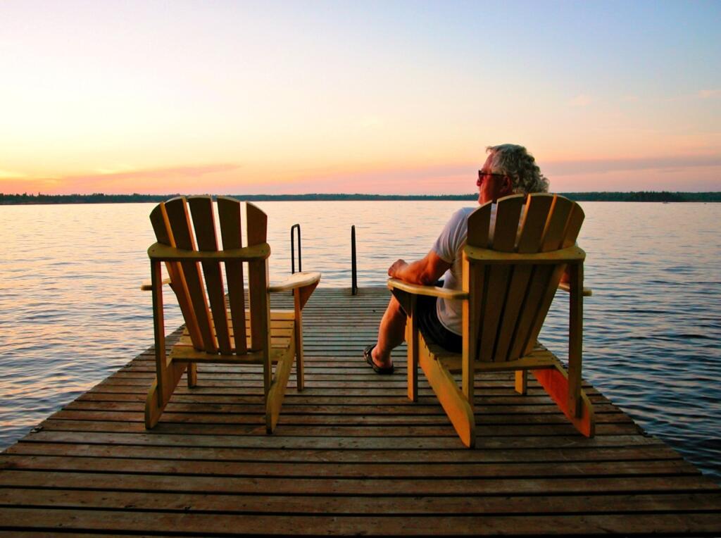 Older retired man relaxing on dock at lake