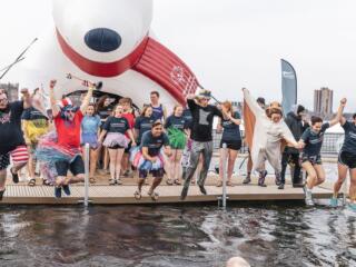 People dressed in costumes jumping into Lake Nokomis for a polar plunge