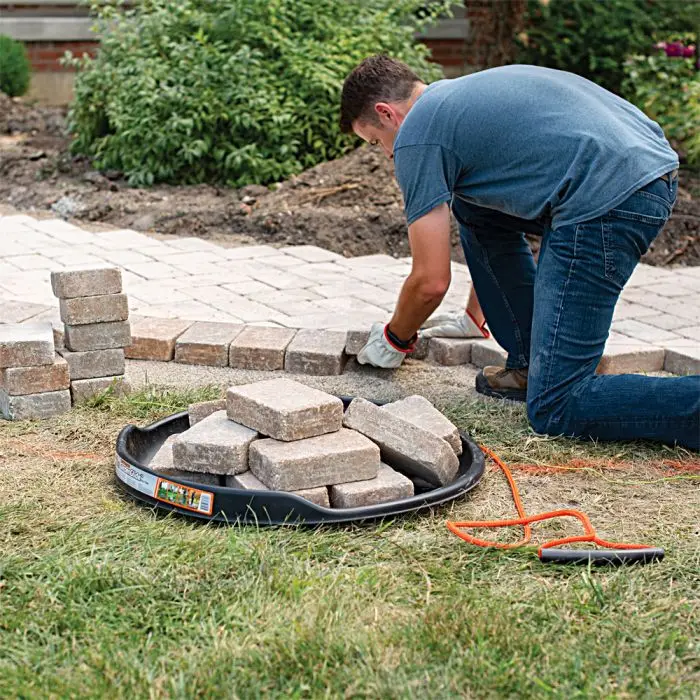 a man stacking bricks using the Leonard GardenGlide Transporter