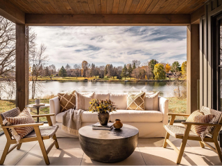 covered patio with sofa, chairs, and round metal cocktail table with lake setting in background