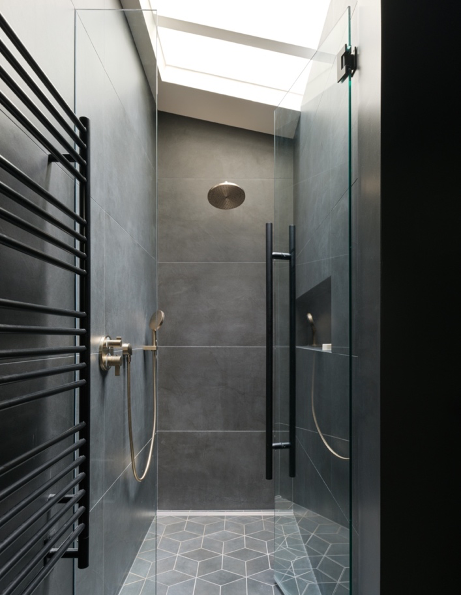 Primary bathroom shower clad in dark tiles in Alden Mason Home, Seattle, WA