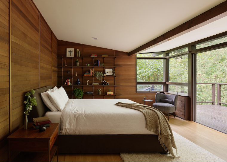 Primary bedroom with wood-paneled walls and an outdoor deck with view of woods on Lake Washington property