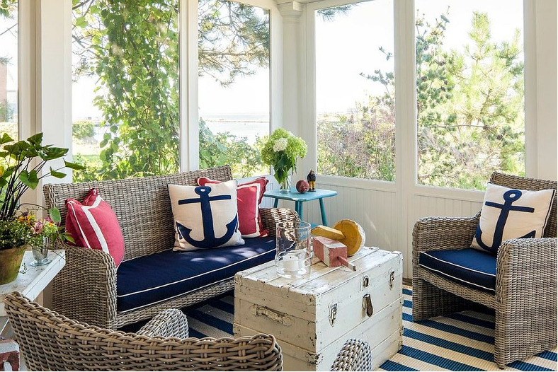 Gulf Coast Lake region sunroom with nautical theme, bright colors, striped rug, weathered antique chest coffee table, large windows, water views