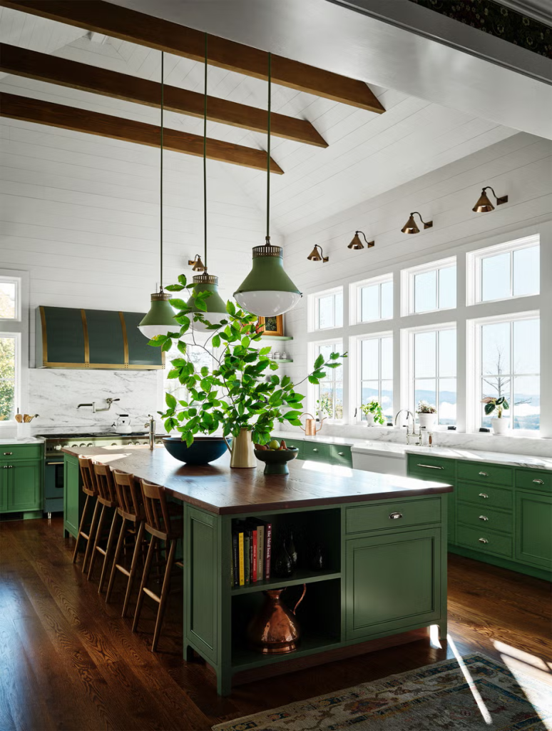 Multi-funcitonal island with drawers, shelves, counter stools painted in deep green with natural wood counter surface, green cabinetry, green range hood